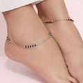 A sterling silver rhodium-plated box chain anklet with black beads, displayed on a person's ankle.