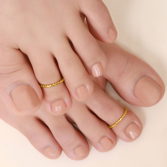 Woman's feet wearing textured gold plated 925 Sterling Silver toe rings. Classic jewellery for women. – Zavya