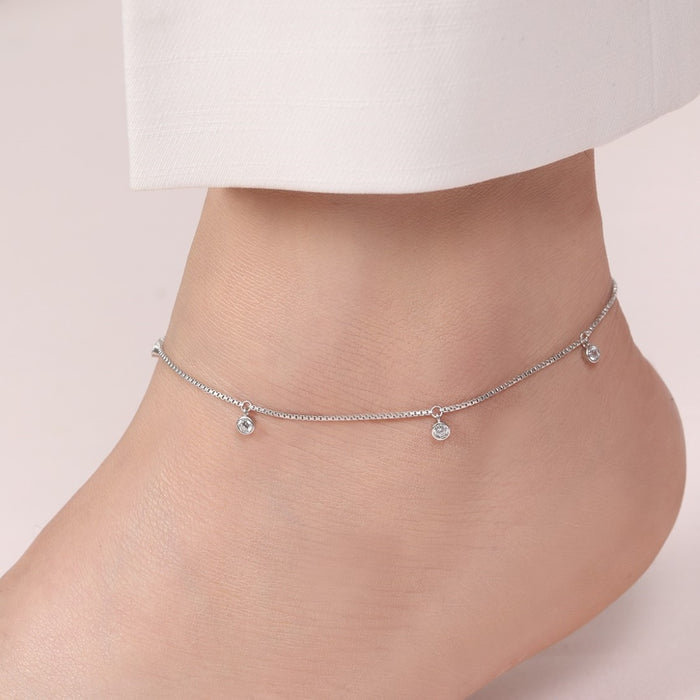 Woman's ankle wearing a delicate CZ drop 925 Sterling Silver anklet. Elegant women's jewellery. – Zavya