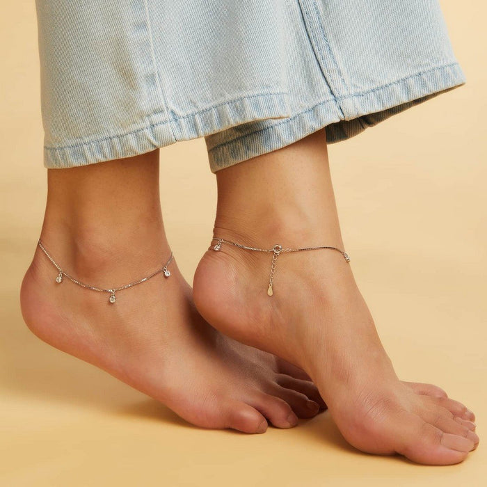 Woman wearing a drop CZ 925 Sterling Silver Anklet on bare ankles. Silver jewelry for women. – Zavya