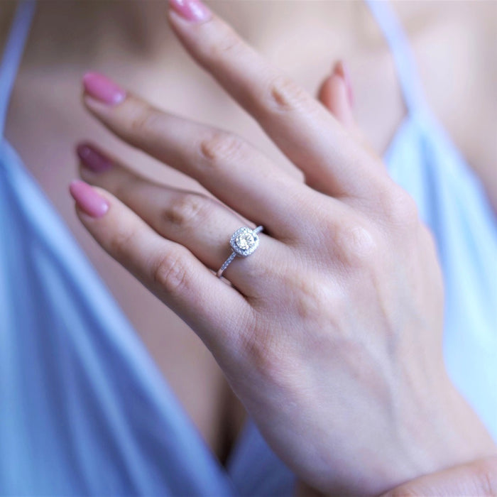 Woman's hand wearing a sparkling 925 Sterling Silver solitaire ring with a crystal halo. – Zavya