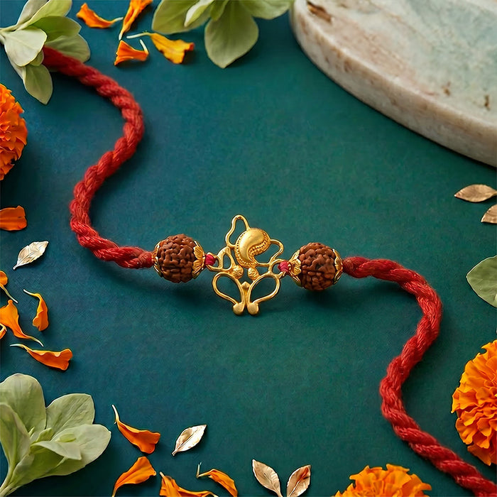 A red braided rakhi silver bracelet with a gold plated ganesha two brown rudraksha beads,