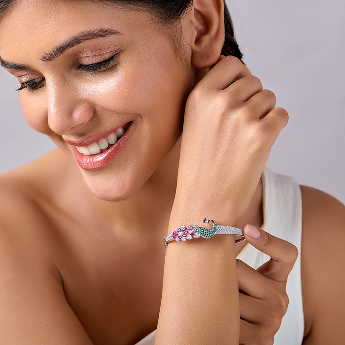 Smiling woman wearing a 925 Sterling Silver peacock bracelet with pink & green stones. Jewellery for women – Zavya