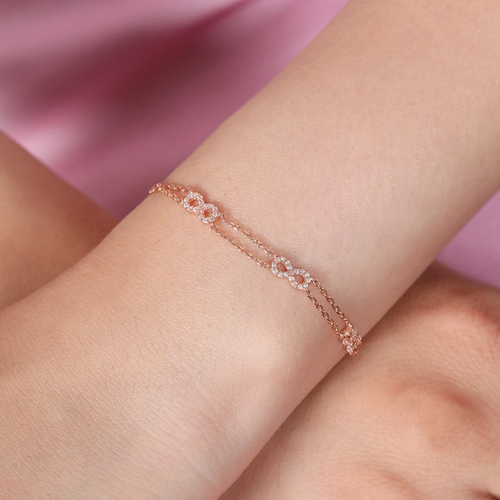 Woman's wrist wearing a 925 Sterling Silver double chain infinity bracelet with crystal charms. – Zavya