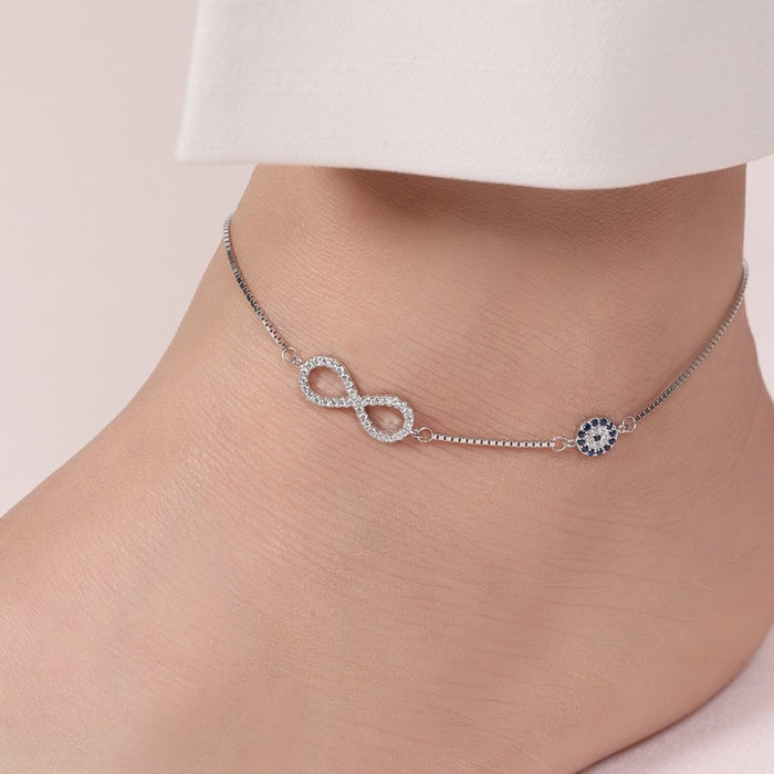 Woman's ankle with a 925 Sterling Silver anklet featuring evil eye and infinity charms. Women's jewelry – Zavya