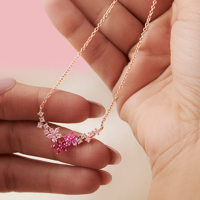 Hands holding a women's 925 Sterling Silver rose gold-plated flower necklace with pink stones. – Zavya
