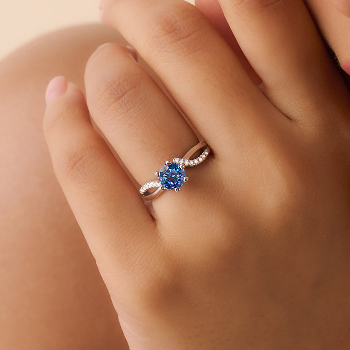 Woman's hand wearing a 925 Sterling Silver blue solitaire ring with a twisted band. Women's jewellery – Zavya