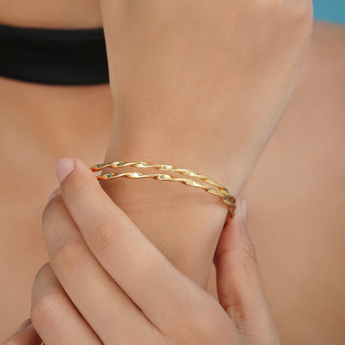 Woman wearing a gold-plated 925 Sterling Silver abstract bangle bracelet on her wrist. Women's jewellery – Zavya