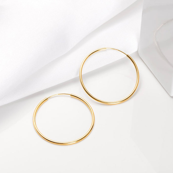 Two golden 925 Sterling Silver hoop earrings for women on white fabric. Daily wear jewellery – Zavya