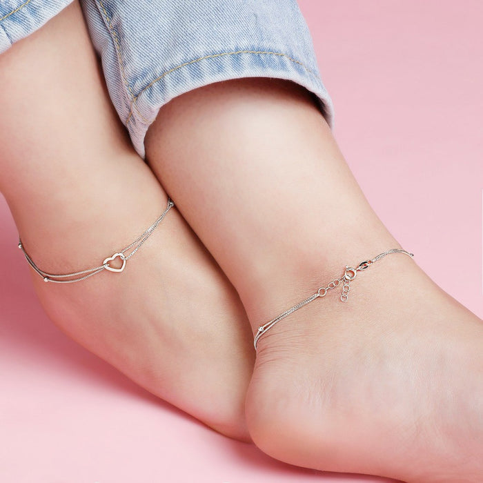 Woman wearing a layered 925 Sterling Silver heart anklet. Delicate silver jewelry for women – Zavya