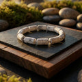 Bracelet with natural stone beads on a wooden surface with a stone background