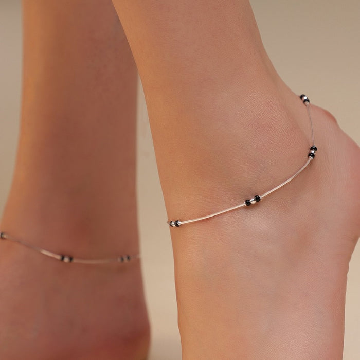 Woman wearing a delicate 925 Sterling Silver anklet with black beads. Silver jewellery for women – Zavya