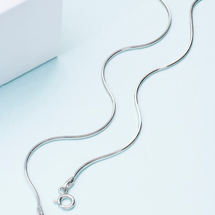 Sleek 925 Sterling Silver snake chain anklet for women on a light blue surface. Minimalist everyday jewellery – Zavya