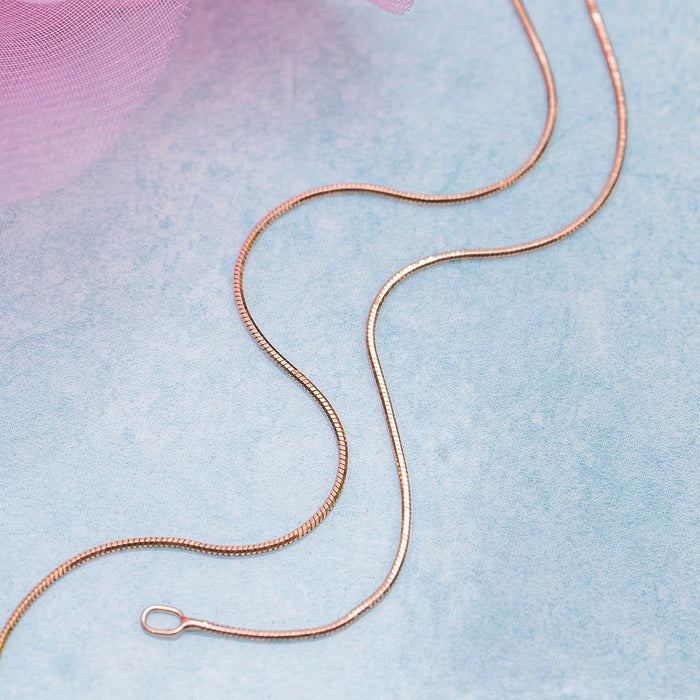 Wavy golden 925 Sterling Silver snake chain anklet for women. Elegant jewellery on light blue background. – Zavya