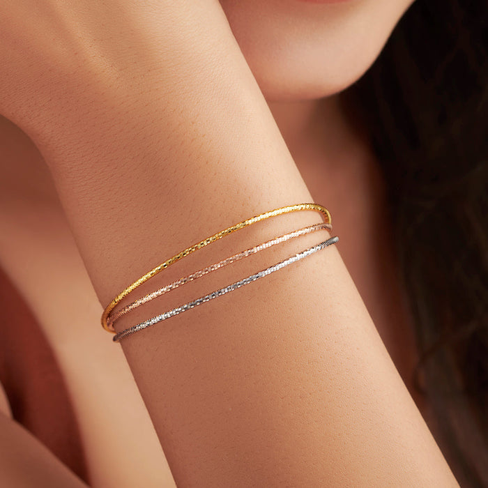 Woman wearing a layered multi-strand 925 Sterling Silver bracelet in gold, rose gold & silver – Zavya