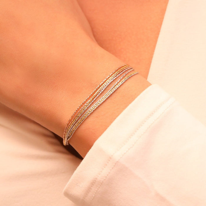 Woman wearing a triple tone 7-chain 925 Sterling Silver bracelet. Layered fine jewelry for women – Zavya