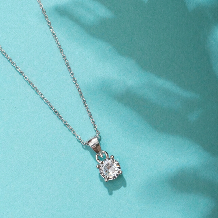 Silver necklace with a diamond pendant on a light blue background